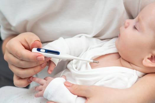 Concerned mother gently measures her sleeping baby's fever with a digital thermometer