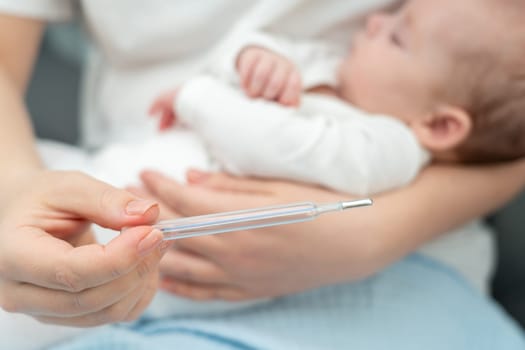 Concerned mother uses a classic thermometer to measure her baby's temperature, showcasing vigilant