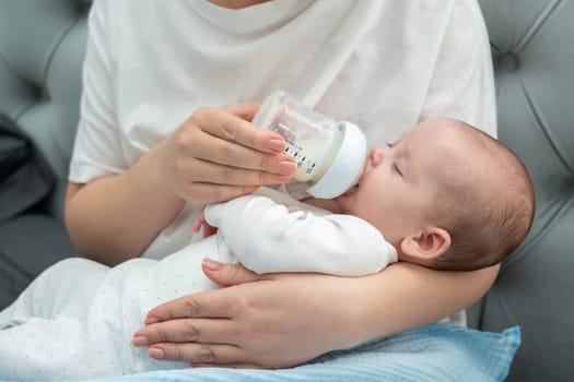 Little newborn eagerly drinks milk formula from a bottle, showcasing the bond and care during