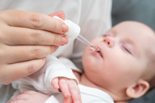 While cradling her sleeping baby, mother gently buries oral drops using a pipette ensuring utmost