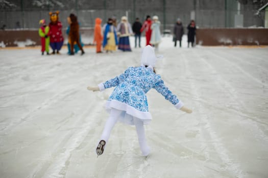 Child on skates. Ice rink in winter. Active lifestyle in winter. Girl is engaged in figure skating. Skaters movements.