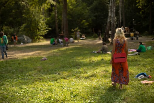 Girl at festival. Woman in summer in nature. Camping details. Man walks on grass.