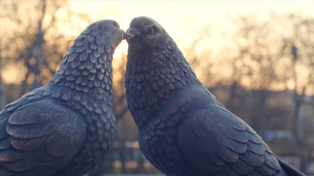 Pair of vintage white pigeon made of bronze and sun background. figurines pigeons made of metal. Two figurines of pigeons like a the monument of love. the monument of love made of bronze HD