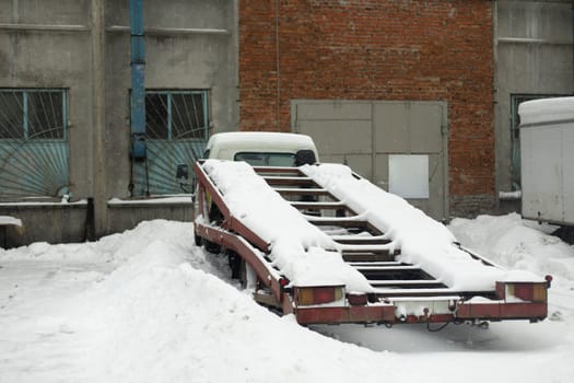 Transporter in snow. Loader in parking lot in winter. Truck for transportation.