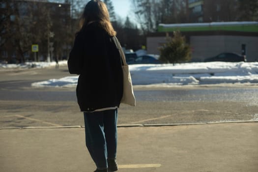 Girl is waiting for bus. Student at bus stop in Russia. Girl by road. Waiting for transport.