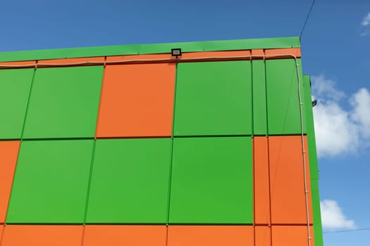 Corner of building. Modern architecture. Green and orange color in exterior of building. Details of house.