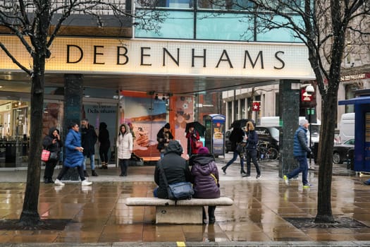 London, United Kingdom - February 01, 2019: People in front of Debenhams store Oxford Street branch on a rainy day. British multinational retailer was formed in 1778.