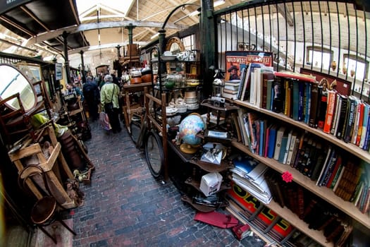 London, United Kingdom - April 01, 2007: Extreme wide angle - fisheye - photo. Stalls with various used stuff, mostly books, shoppers in background at Camden Lock, famous flea market in UK capital.