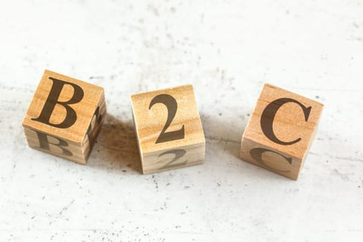 Three wooden cubes with letters B2C (stands for Business to Customer) on white board.