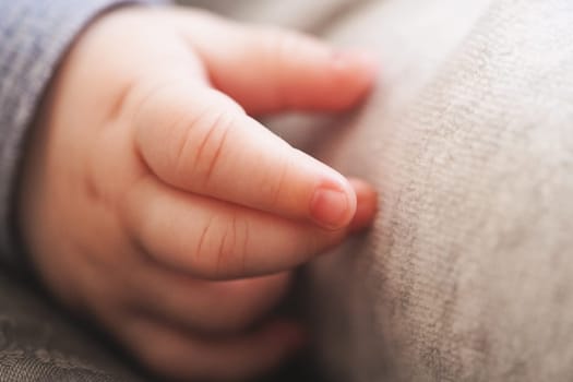 Infant baby boy hand close up, shallow depth of field photo only his finger in focus. Abstract motherhood background