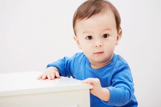 Baby, portrait and balance for walking steps in home for childhood development, safety or mockup space. Boy, kid and face or holding furniture for growing support or progress, learning or curious.