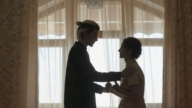 Couple is discussing something at window. Stock. Young man confesses his love to woman at window. Guy with young woman talking about serious things aside.