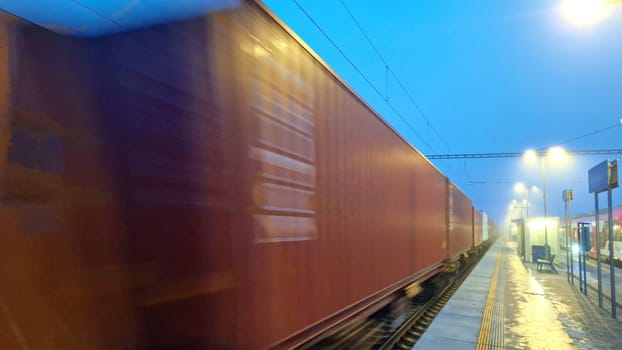 Night train in the fog. Station in fog and darkness. Passing of freight train in fog and darkness. Concept of traffic problems, cargo train moving through station. Concept of rail haulage and globalisation.