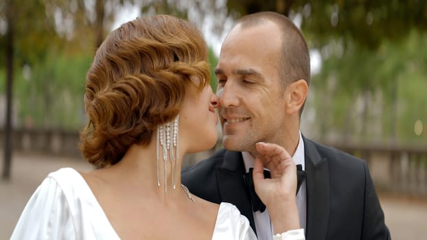 Beautiful couple of bride and groom in park. Action. Portrait of woman with short curly hair embracing her man