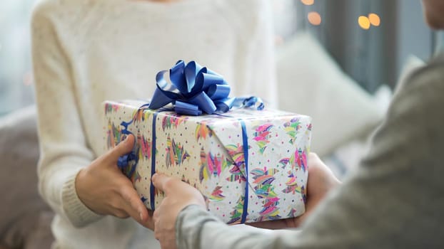 Valentine's Day concept. A loving couple celebrating Valentine's Day in the restaurant. Lovers give each other gifts. Couple giving each other Christmas gifts. Couple giving a gift box to each other