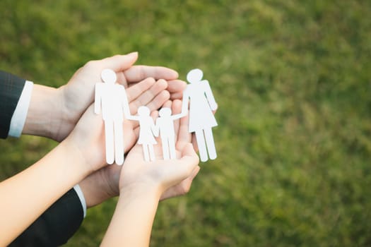 Background of paper family icon held in hand symbolize dedication to environmental friendly lifestyle of modern family, parenthood guiding sustainable lifestyle to their children. Gyre