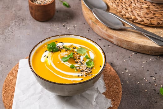 Delicious homemade creamy pumpkin soup with cream with sesame seeds and watercress.