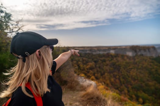 woman on mountain peak looking in beautiful mountain valley in autumn. Landscape with sporty young woman, blu sky in fall. Hiking. Nature.