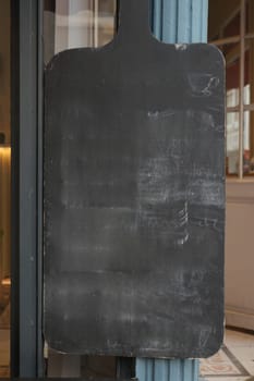 Empty wooden blackboard mockup standing outdoors in front of cafe .