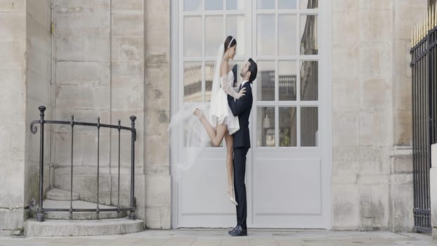 Beautiful date photo shoot. Action.A young girl in a short dress and a man lifting her and sitting in front of the architecture. High quality 4k footage