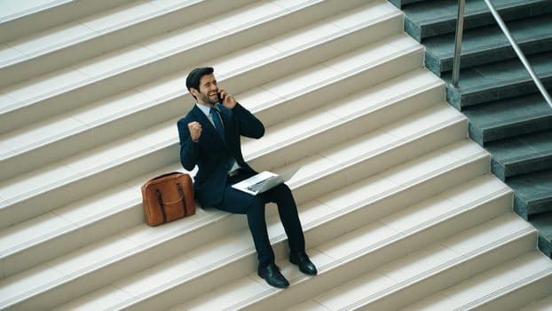 Top view business man celebrate successful project while sitting at stairs. Smart project manager getting new job, getting promotion, increasing sales while calling friends by using phone. Exultant.