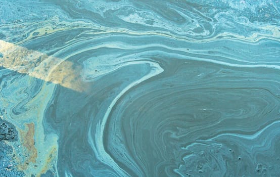 A marble texture of a rainbow spill of gasoline on a sidewalk in a puddle as a background.