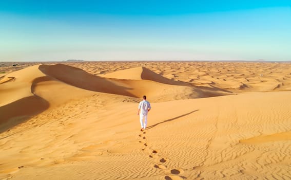 Dubai desert sand dunes, men on Dubai desert safari, United Arab Emirates vacation, men on vacation in Dubai Emirates walking in the sand dunes