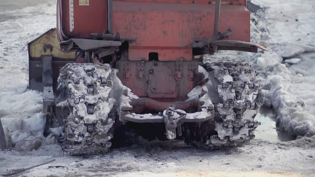 The back of a large technical machine. CLIP. The wheels drive the car back through the snow. Heavy equipment rides in the snow on metal tracks.