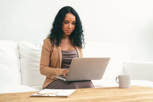 African-American woman using laptop computer for crucial work on internet. Secretary or online content writing working at home.