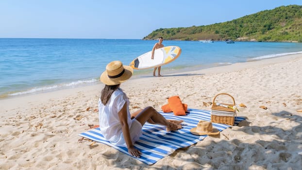 Koh Larn Island near Pattaya Thailand, the tropical beach of Koh Larn Thailand, a white beach with clear water ocean. Tropical Island. a couple of men relaxing on the beach with a sup board