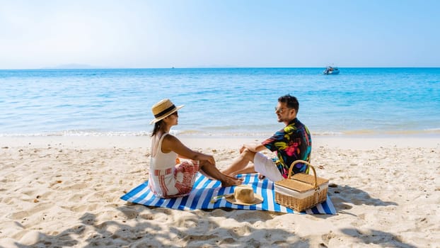 Koh Larn Island near Pattaya Thailand, the tropical beach of Koh Larn Thailand, a white beach with clear water ocean. Tropical Island. a couple of men relaxing on the beach with a picnic