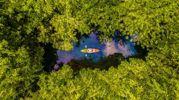couple in a kayak in the jungle of Krabi Thailand, men and women in a kayak in a tropical jungle in Krabi mangrove forest. top view of kayak in rainforest with drone