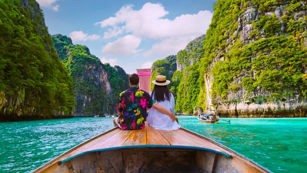 Couple in front of Longtail boat at the lagoon of Koh Phi Phi Thailand during vacation. green blue turqouse colored ocean of Koh Phi Phi Thailand