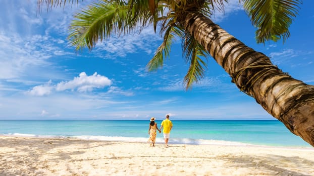 Tropical Island Koh Kood or Koh Kut Thailand Men and women on vacation walking under a palm tree at a white beach at Koh Kut Island Thailand