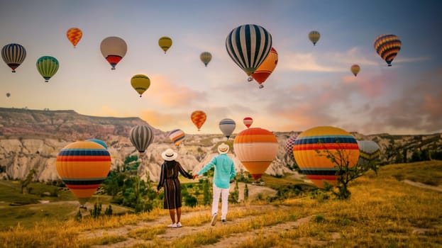 Cappadocia Turkey during sunrise, a couple mid age men and women on vacation in the hills of Goreme Cappadocia Turkey, men and woman looking sunrise with hot air balloons in Cappadocia Turkey