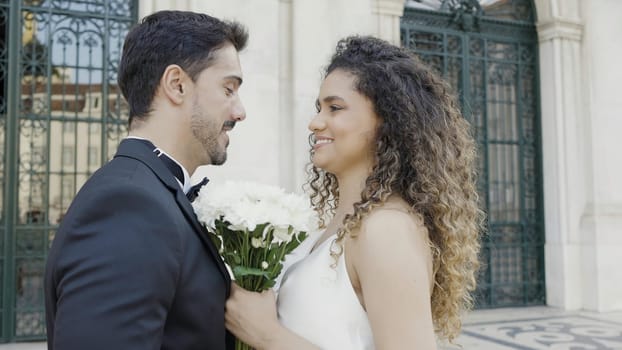 Young and beautiful wedding couple stands together near retro architecture building. Action. Lovely groom and bride on their wedding day