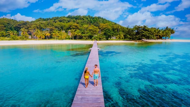 couple man and woman on a wooden boardwalk jetty on a tropical Island in Thailand, Koh Kham near Koh Mak Trat, a wooden pier on a tropical island during vacation holidays in Thailand