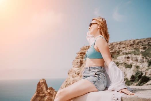 Woman travel sea. Young Happy woman in a long red dress posing on a beach near the sea on background of volcanic rocks, like in Iceland, sharing travel adventure journey