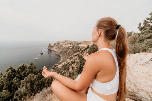 Middle aged well looking woman with black hair doing Pilates with the ring on the yoga mat near the sea on the pebble beach. Female fitness yoga concept. Healthy lifestyle, harmony and meditation.