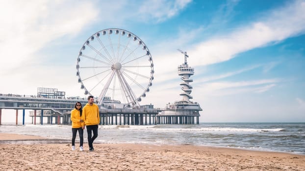 a couple of men and woman on the beach of Scheveningen Netherlands during Spring, The Ferris Wheel at The Pier at Scheveningen in the Netherlands, Sunny spring day at the beach of Holland