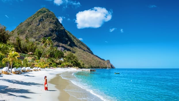 St Lucia Caribbean, woman on vacation at the tropical Island of Saint Lucia Caribbean ocean, an Asian woman in red dress walking on the beach