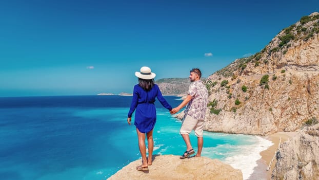 couple on vacation Turkey Kaputas Beach Kas Turkey, white orange beach from cliffs by the ocean of Kas Turkey rivera during summer, men and woman standing on cliff looking ocean during summer vacation