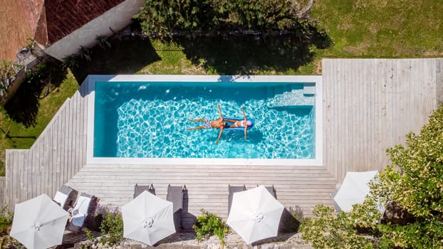 two people swim in the pool at the hotel. View from above at a couple of men and women in a swimming pool of a luxury vacation home in France Europe