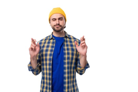 young brutal brunette man with a beard and mustache crossed his fingers in anticipation.