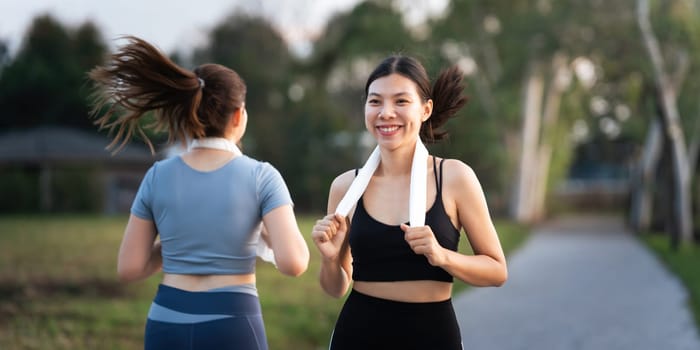 Young smiling sporty woman running in park in the morning. Fitness girl jogging in park.