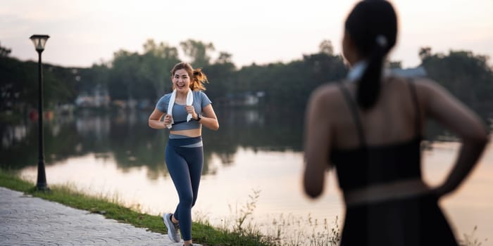 Jogging woman running in park on beautiful day off. Sport fitness model of asian ethnicity training outdoor for marathon.