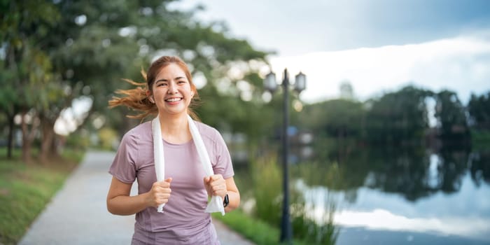 Young smiling sporty woman running in park in the morning. Fitness girl jogging in park.