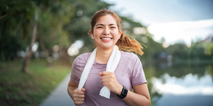 Young smiling sporty woman running in park in the morning. Fitness girl jogging in park.