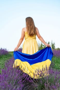 Ukrainian flag in the hands of a girl, a lavender field in Ukraine.