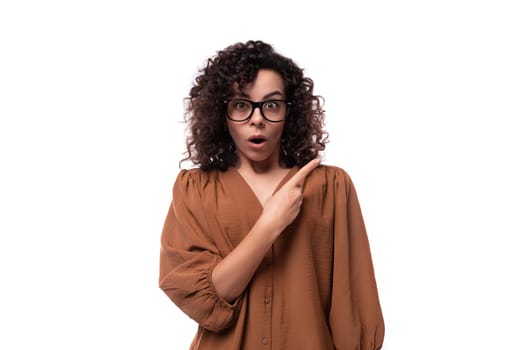 young shocked caucasian curly brunette woman dressed in stylish brown shirt.